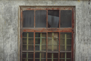 Fototapeta na wymiar Window with broken glass in old building Wooden window frame with partially broken glass in old abandoned brick building