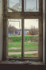 Window with broken glass in old building Wooden window frame with partially broken glass in old abandoned brick building