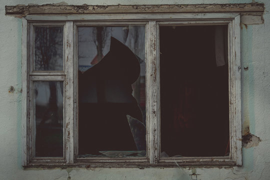 Window with broken glass in old building Wooden window frame with partially broken glass in old abandoned brick building