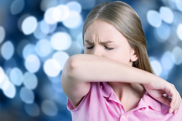 Young woman scratching her nose with elbow on dark gray background