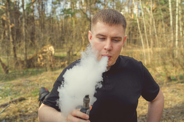 Overweight man smoking near forest Plus size adult male exhaling thick fume while smoking on cloudy day near forest