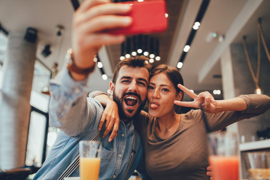Young happy couple at cafe taking selfie - Powered by Adobe