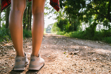 Happy young Asian woman traveler with backpack walking in forest. Hiker Asian woman with backpack walking on path in summer forest. Adventure backpacker travel people concept.