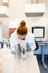 The girl in the lab looking through a microscope. The girl works in a scientific laboratory.