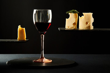 Composition of fragrant red wine in glass and pieces of hard cheese