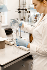 Fototapeta premium A young girl conducting experiments in a scientific laboratory. A young scientist in a modern laboratory. Student in the lab.