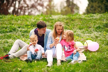 Fototapeta premium Happy family on picnic in flowered park sitting on grass, parenthood leisure in nature