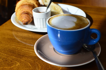 cup of coffee and croissant on wooden table