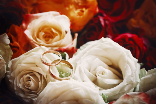 Two wedding rings placed on the bouquet of roses. Close up image.