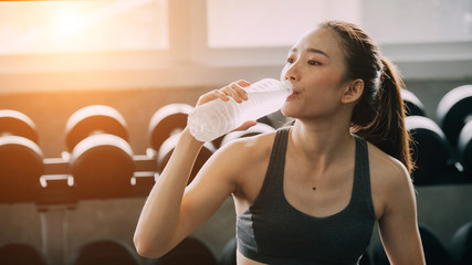 Female drinking bottle of water  in the gym. © nikomsolftwaer