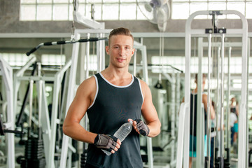 Fototapeta na wymiar Man drinking water in the gym. Young man drinking water and taking a break after workout in gym,