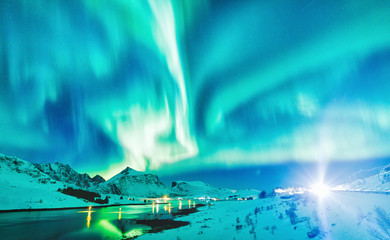Aurora Borealis natural phenomenon on Lofoten Islands in Norway, Scandinavia, Europe. Night sky with northern lights over mountains and road reflected in fjord. Night winter landscape with aurora.