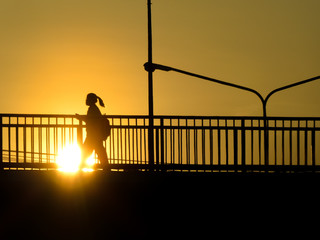 Silhouette of unknown city people walking across the overpass (Flyover) with sunset as a backdrop. Bangkok, Thailand.