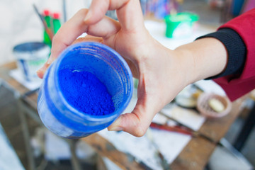 woman holding blue pigment powder for painting
