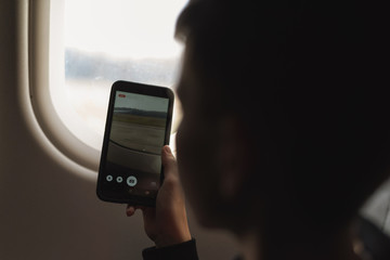 Caucasian boy using smartphone and taking picture during air flight.  Safety travel with kid. concept