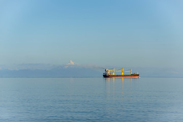empty cargo container ship on an empty open ocean with mountain background