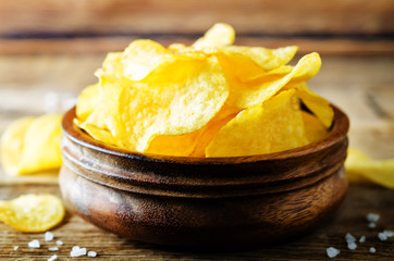 Potato chips with salt on a wood background
