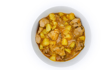 A plate of stewed and potatoes on isolated white background. Stirring with a spoon of meat and broth, top view. Ragout of natural potatoes and meat.