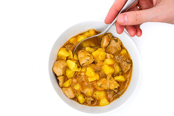 Spoon in hand and natural food cooked at home. A plate of Turkey stewed and potatoes on isolated white background. Ragout of ripe potatoes and Turkey.