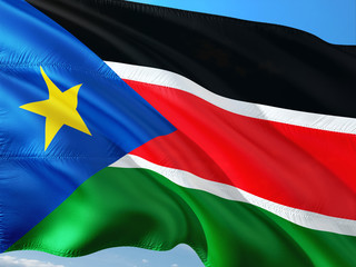 Flag of South Sudan waving in the wind against deep blue sky. High quality fabric.