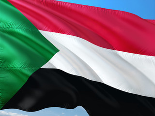 Flag of Sudan waving in the wind against deep blue sky. High quality fabric.