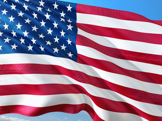 Fototapeta premium Flag of United States waving in the wind against deep blue sky. High quality fabric.
