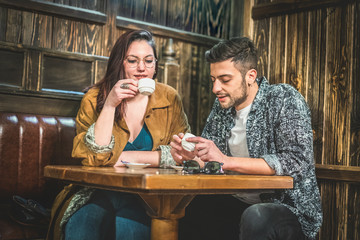 Young couple drinking espresso coffee in a wooden designed restaurant