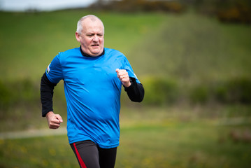 Fototapeta premium Senior man in 60s exercising and keeping fit by running in a park