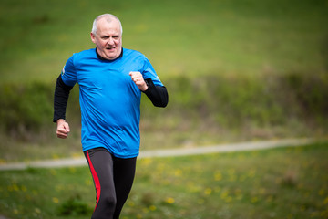 Senior man in 60s exercising and keeping fit by running in a park