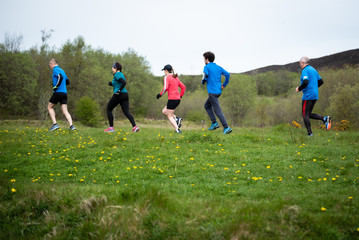 Group of people of mixed ages running together outside, preparing for the marathon