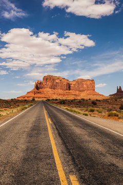 A Road Leading To A Rugged Rock Formation In The Desert; Arizona, United States Of America