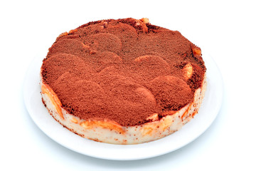Pie sprinkled with cocoa powder on a plate. Chocolate cream pastry crackers cake, close-up. Chocolate cookie cake on isolated white background.