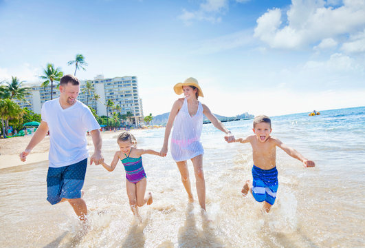 A Family Of Four Enjoying A Summer Vacation In Waikiki Beach; Honolulu, Oahu, Hawaii, United States Of America