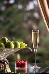 Glass of sparking wine and vase of fruits