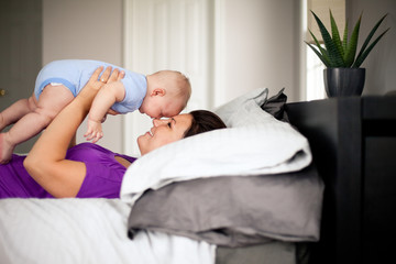Mother Holding Baby Boy on Bed in Bedroom