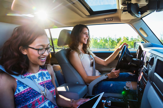 Two young women driving in a car on a road trip; Edmonton, Alberta, Canada