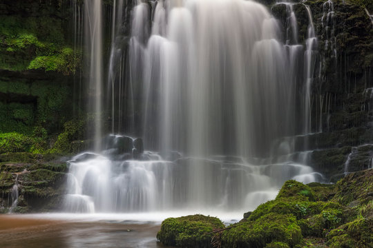 Numerous waterfalls flowing over rocks into a pool in the Yorkshire Dales; Settle, North Yorkshire, England
