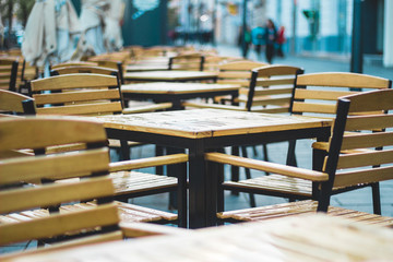 Small empty terrace with nobody in it with wooden chair and tables on a rainy day – Casual local on the sidewalk in the city