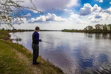 Fototapeta na wymiar Fisherman fishes spinning on the river bank