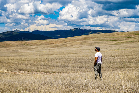 Standing in a vast farm field looking towards the mountains; Utah, United States of America