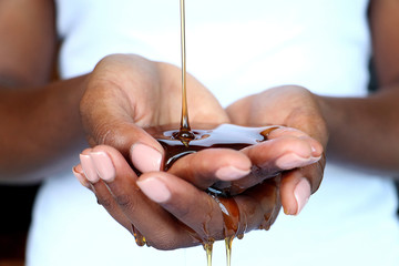 Black African hands cupped holding pouring honey for beauty purposes