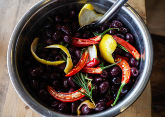 Black, greek Kalamata olives marinated with chilli, lemon rind and rosemary in a silver bowl