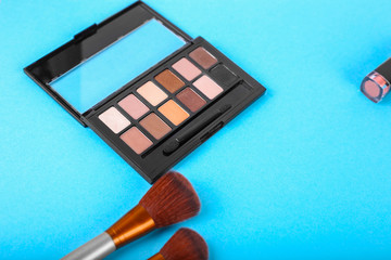Top view of eyeshadow palettes and brushes on blue background.Top view. Flat lay