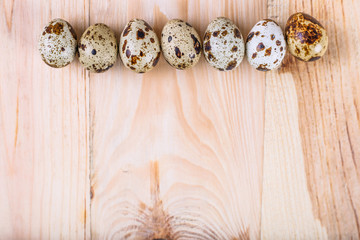 Quail eggs on wooden background with space for text.