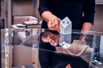 Elegant jewellery shop assistant is showing beatiful pearl earrings for customer.