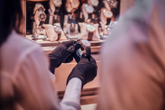 Shop Assistant In Black Gloves Is Showing Expensive Watch For A Customer.