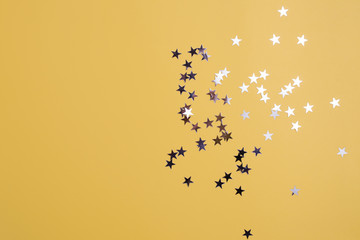 Star-shaped confetti scattered on a yellow background. Celebration and party, concept. Copy space