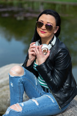 Brunette in sunglasses sits and listens to music in headphones