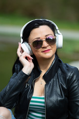 Brunette sits on a street bench and listens to music on headphones