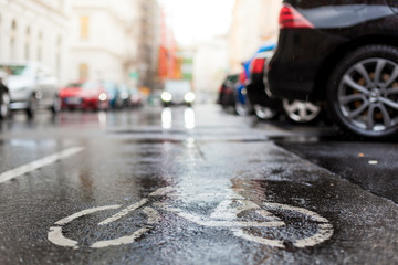 Nasse Straße mit Fahrrad Bodenmarkierung. Nasser Fahrradstreifen mit Straßenmarkierung. Wet cycle lane with bicycle sign on road.